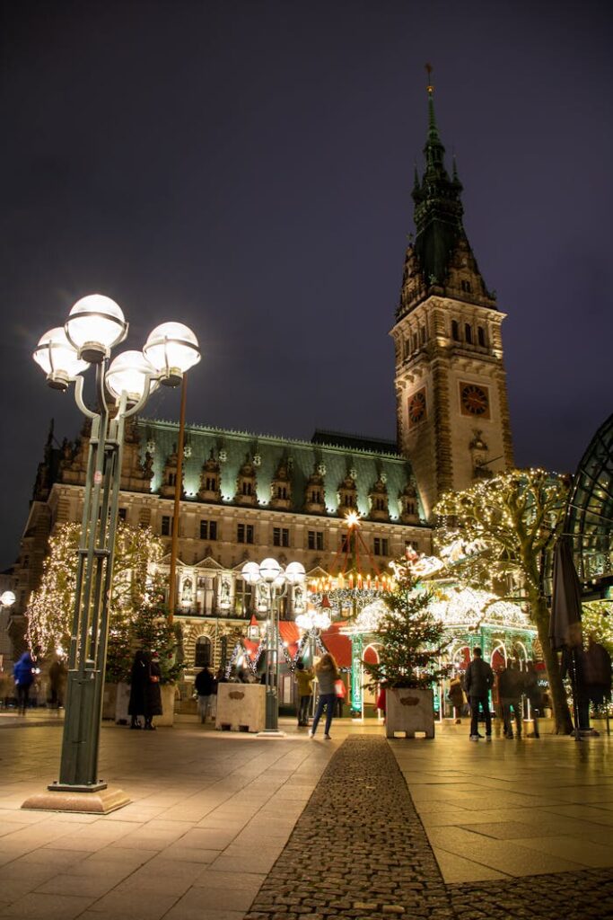 Evening scene at Hamburg Christmas market with festive lights and Town Hall backdrop.